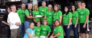 Group of DFW Smiles team members wearing green shirts posing together outdoors.