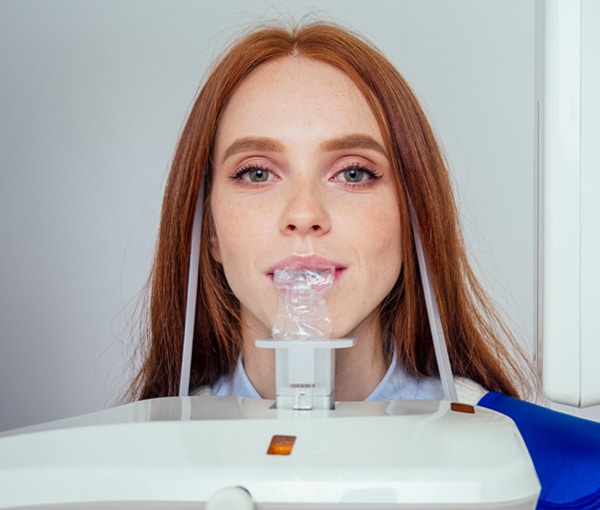 Young woman using intraoral scanner for dental examination in modern dental office setting.