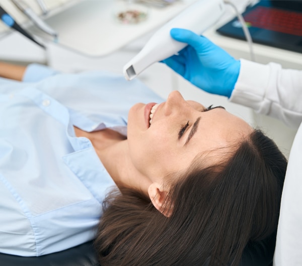 Patient receiving dental examination in professional dentist office with hygienist wearing blue gloves.