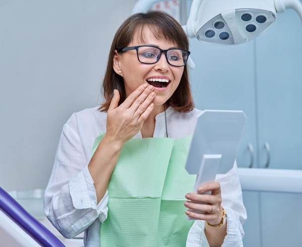 Woman dentist holding tablet in modern dental office, smiling at camera