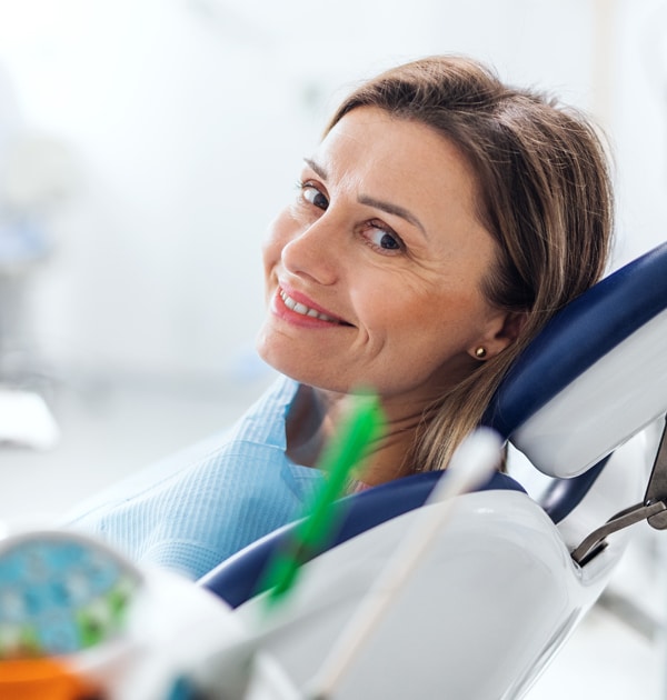 Woman patient smiling in dental chair during examination at modern dental office.