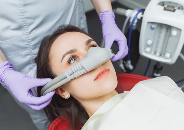Patient receiving dental treatment with nitrous oxide mask in dental office setting.