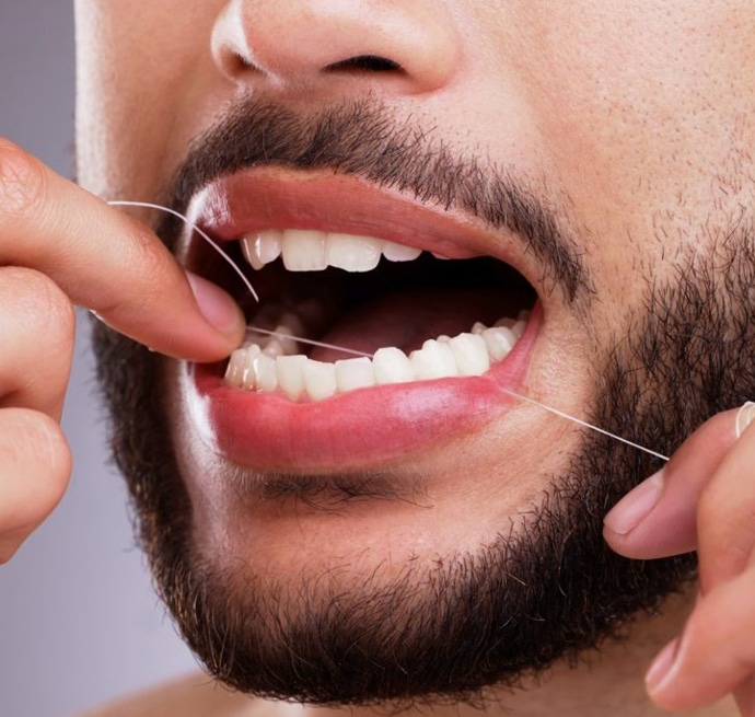 Man flossing teeth with dental floss, demonstrating proper oral hygiene technique.